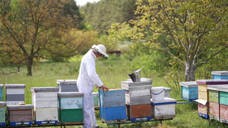 man beekeeper in uniform working on beehive field. beekeeping worker in protective uniform.