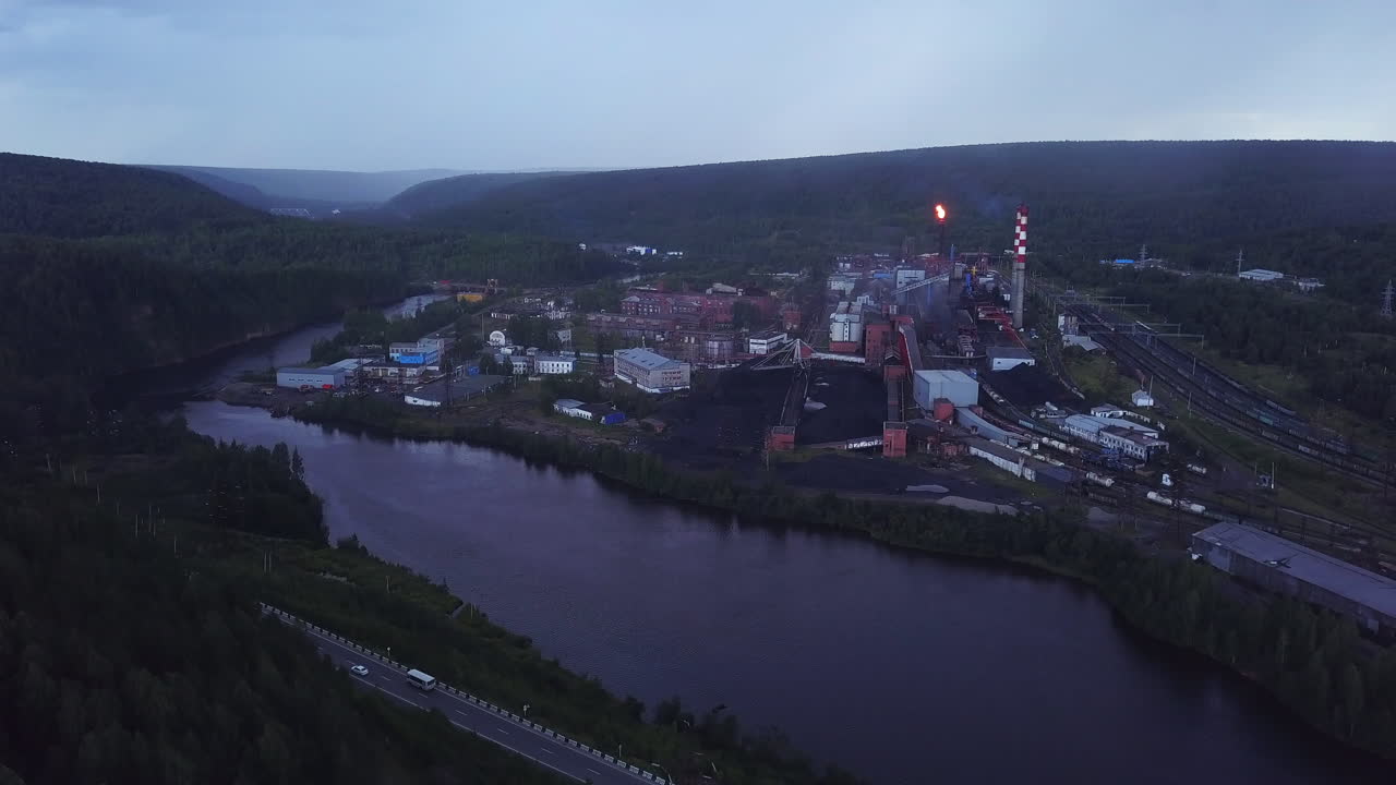 промышленный завод у реки в сумерках