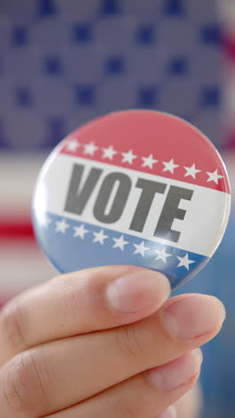 biracial teen girl's hand holds us vote badge in vertical video, slow motion, copy space