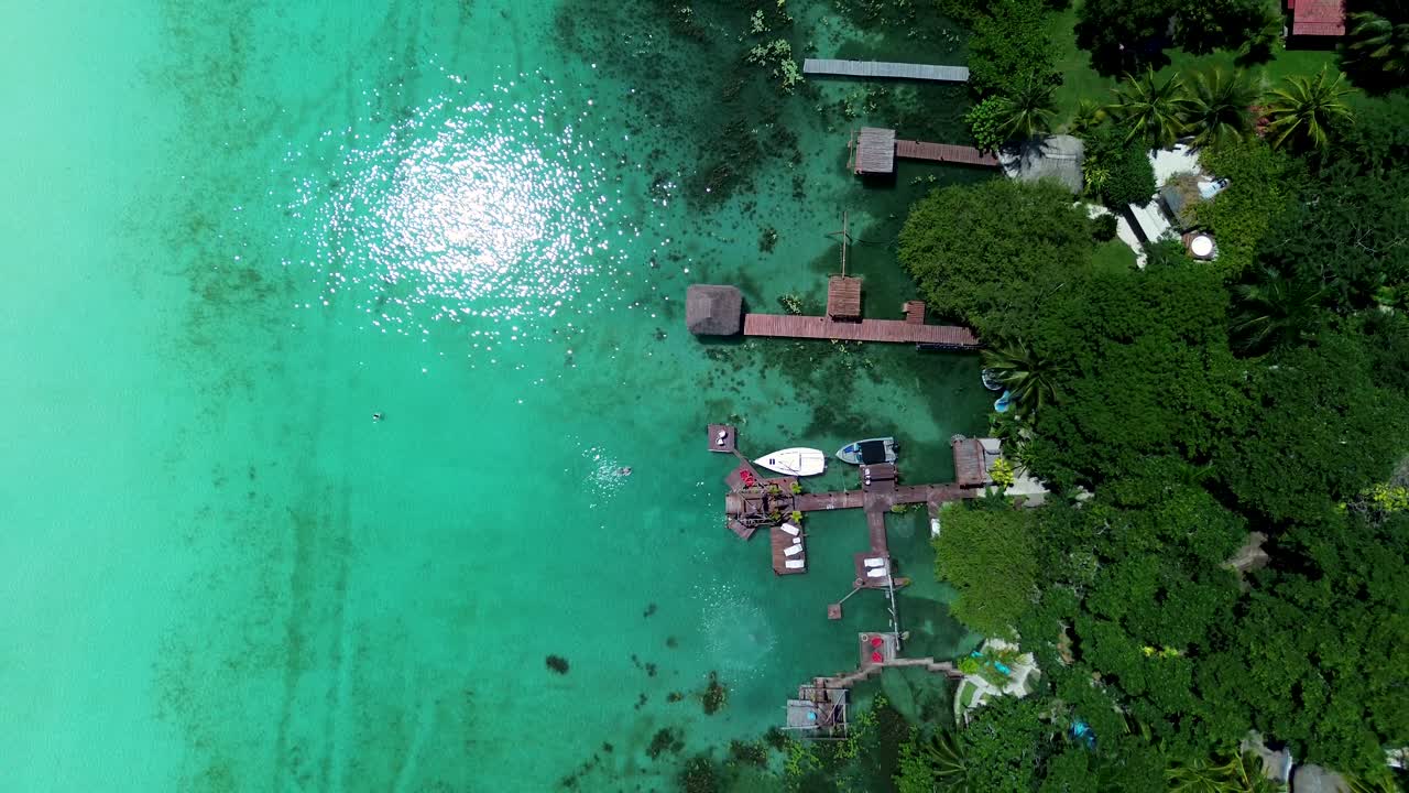 Drone aerial landscape of boats docked by wharf jetty in Bacalar lagoon lake sandbar resort huts restaurants Quintana Roo Mexico travel vacation tourism holidays