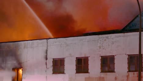 hand-held shot of an apartment fire being fought by firefighters in montreal