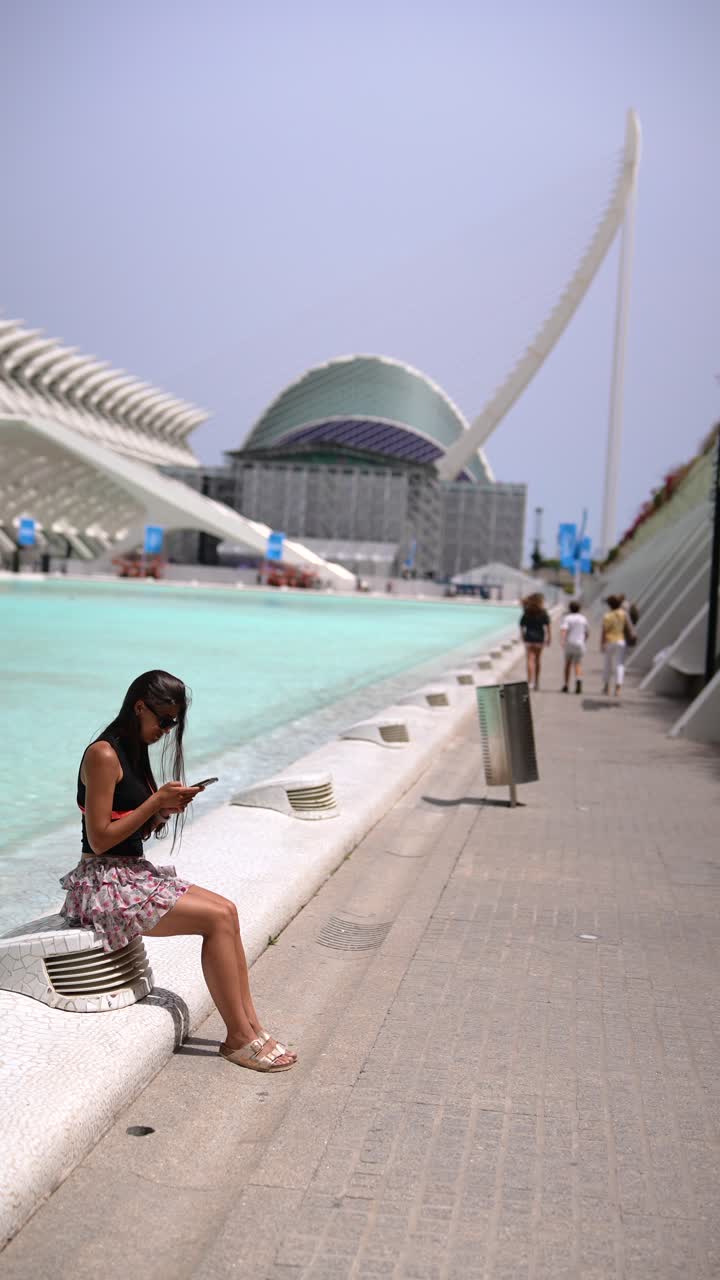 Woman using phone by a modern fountain near museum