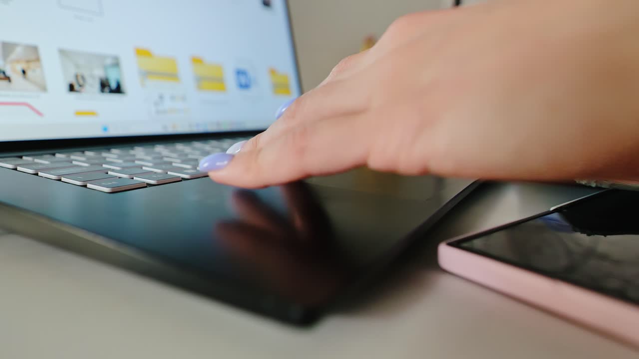 Feminine fingers with lilac nails touch laptop keys in cozy home office