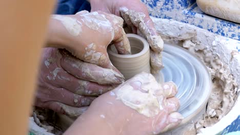 potter's hands work with clay on a potter's wheel