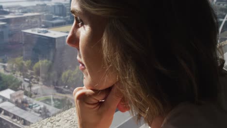 profile of caucasian businesswoman thinking and looking through window