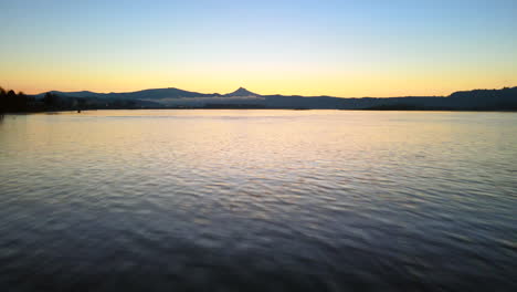 drone volando ligeramente por encima del agua, corriendo sobre el hermoso lago durante un hermoso amanecer