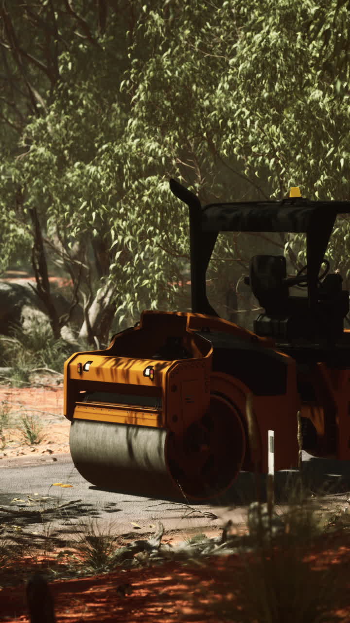 rodillo de carretera amarillo en un camino de tierra en el bosque