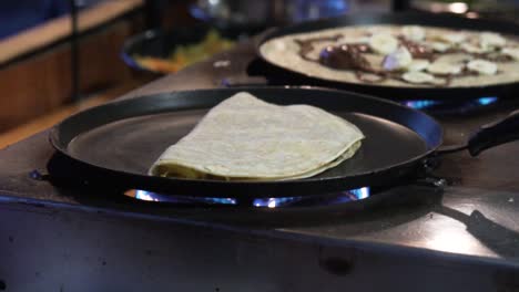 close shot of a folded pancake in a pan in top of a fire