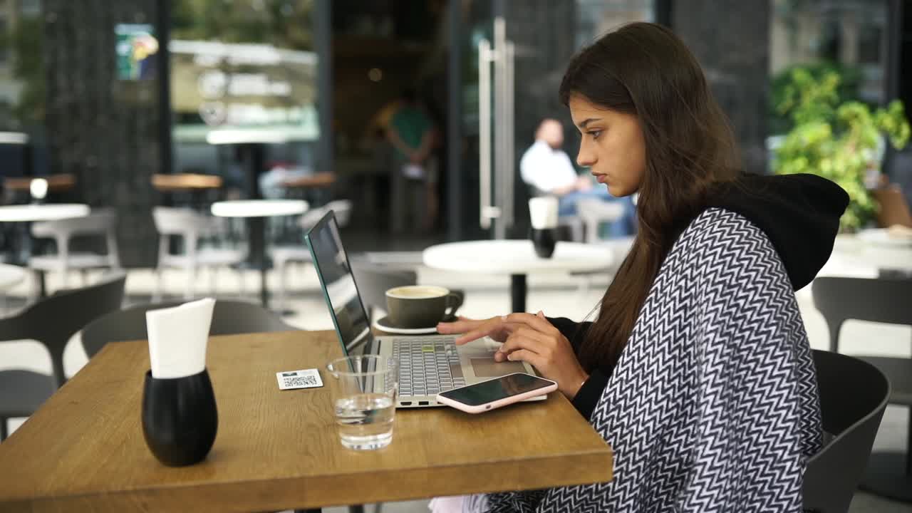 mujer trabajando en una computadora portátil en un café