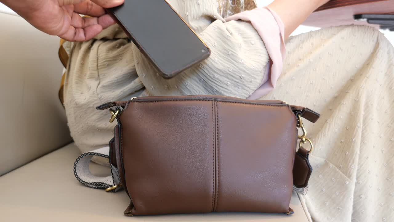 una mujer tiene su teléfono robado de su bolso.