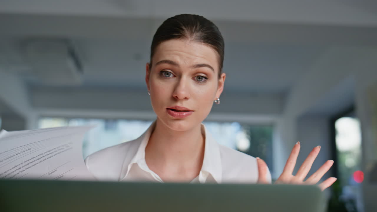 Anxious lady complaining videocall holding documents at workplace closeup