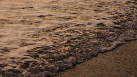 pequeñas olas de agua de mar en cámara lenta vienen a la playa de arena de bali indonesia