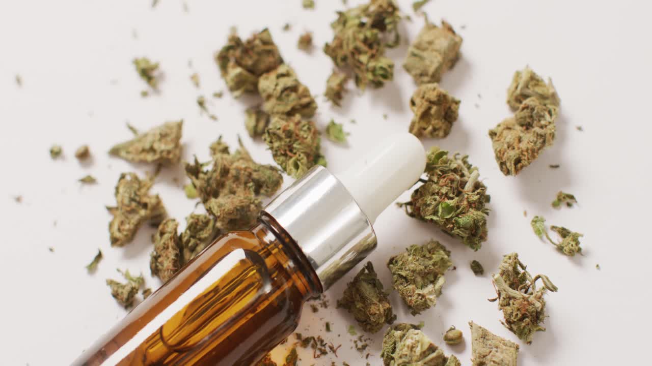 Video de cogollos de marihuana y botella de extracto de CBD sobre fondo blanco