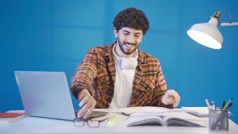 guapo y sonriente joven estudiante sentado en el escritorio trabajando con documentos, tormenta de ideas proyecto creativo con la investigación.