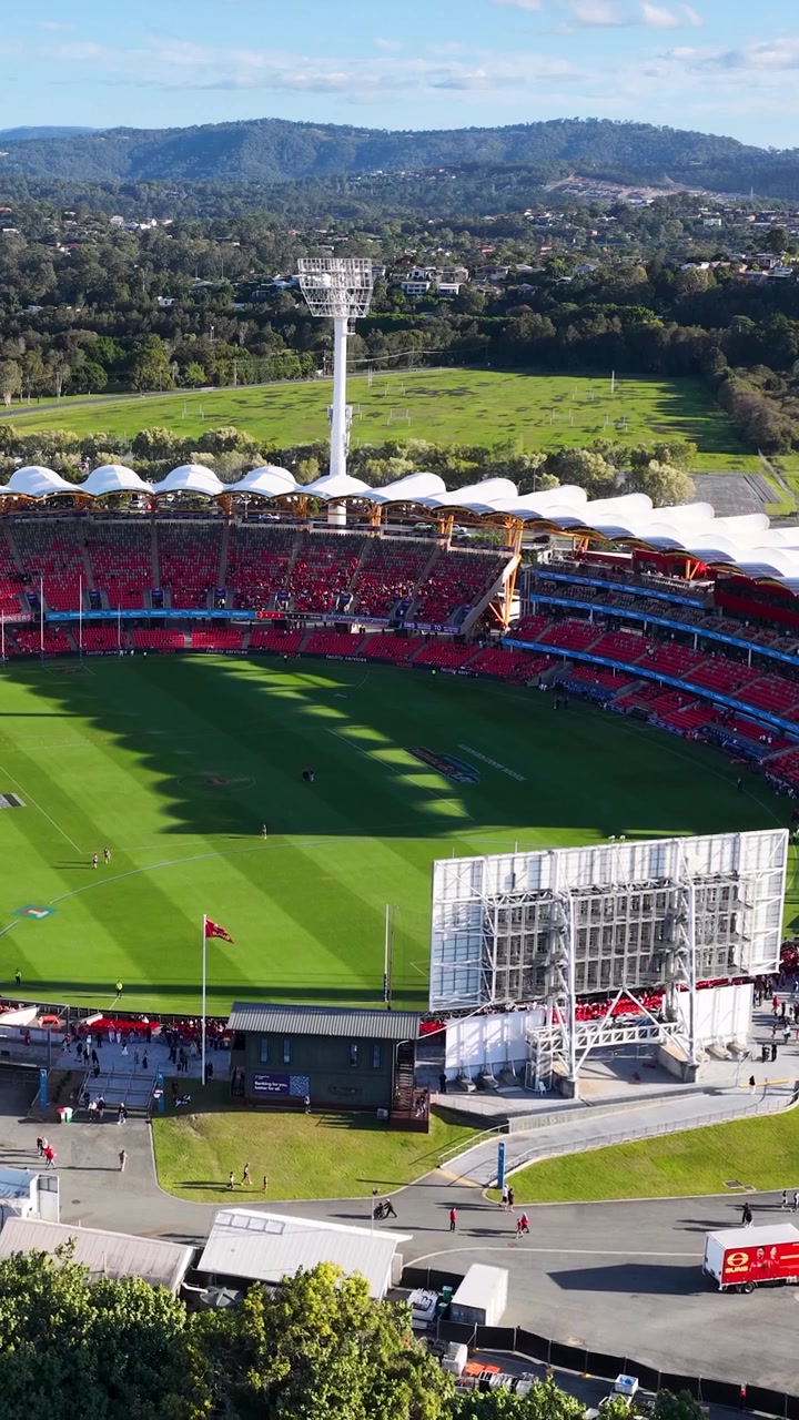 High angle aerial shot of a modern sports stadium with green grass and red seating.