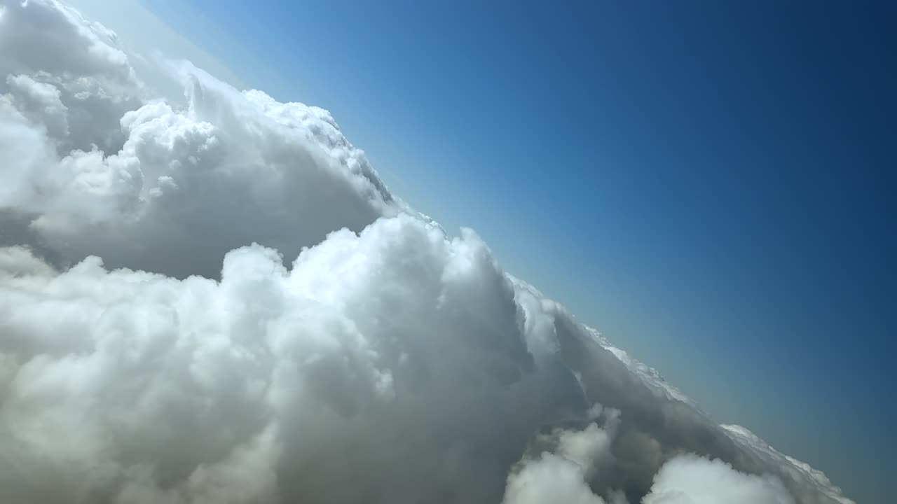An immersive pilot’s perspective from a jet cockpit flying in an abrupt left turn over the tops of cottony clouds under a blue sky
