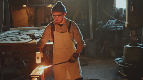 blacksmith hammering red-hot metal on anvil in workshop