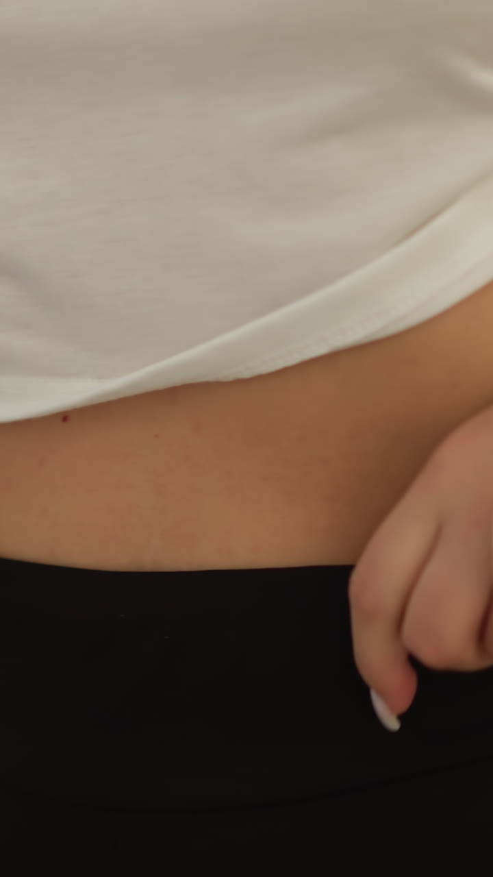 Woman pulls up sportive pants training at home closeup. Lady wearing simple and comfortable tracksuit exercises in domestic gym slow motion