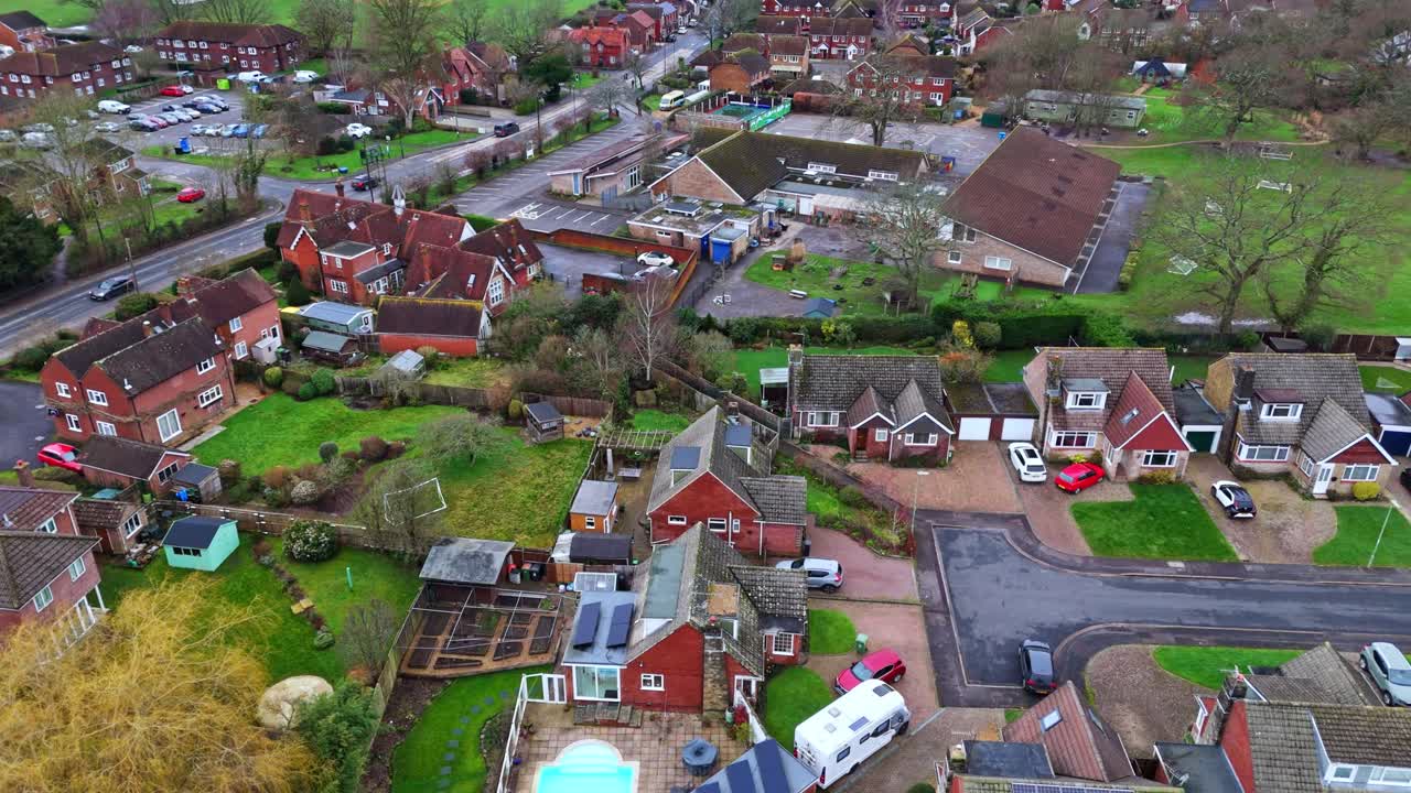 aerial panning drone shot over suburban Southampton with botley village housing at sunset on an overcast cloudy winters day with cars passing by on the roads below past the small housing in the town