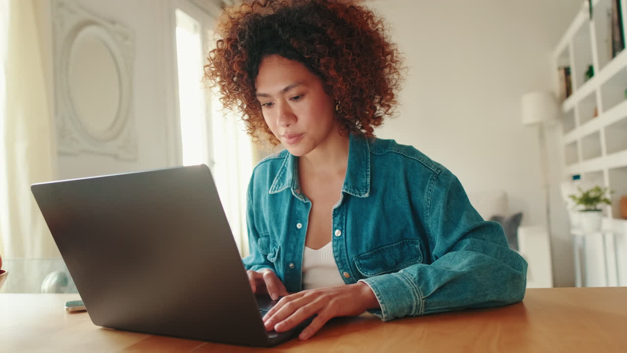 Young Woman Working on Laptop and Using Smartphone at Home
