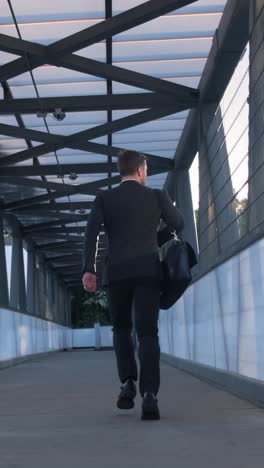 a businessman with a briefcase quickly runs to the office rear view vide a businessman with a briefcase quickly runs to the office rear view a businessman in a black suit with a briefcase rushes to work in the bank