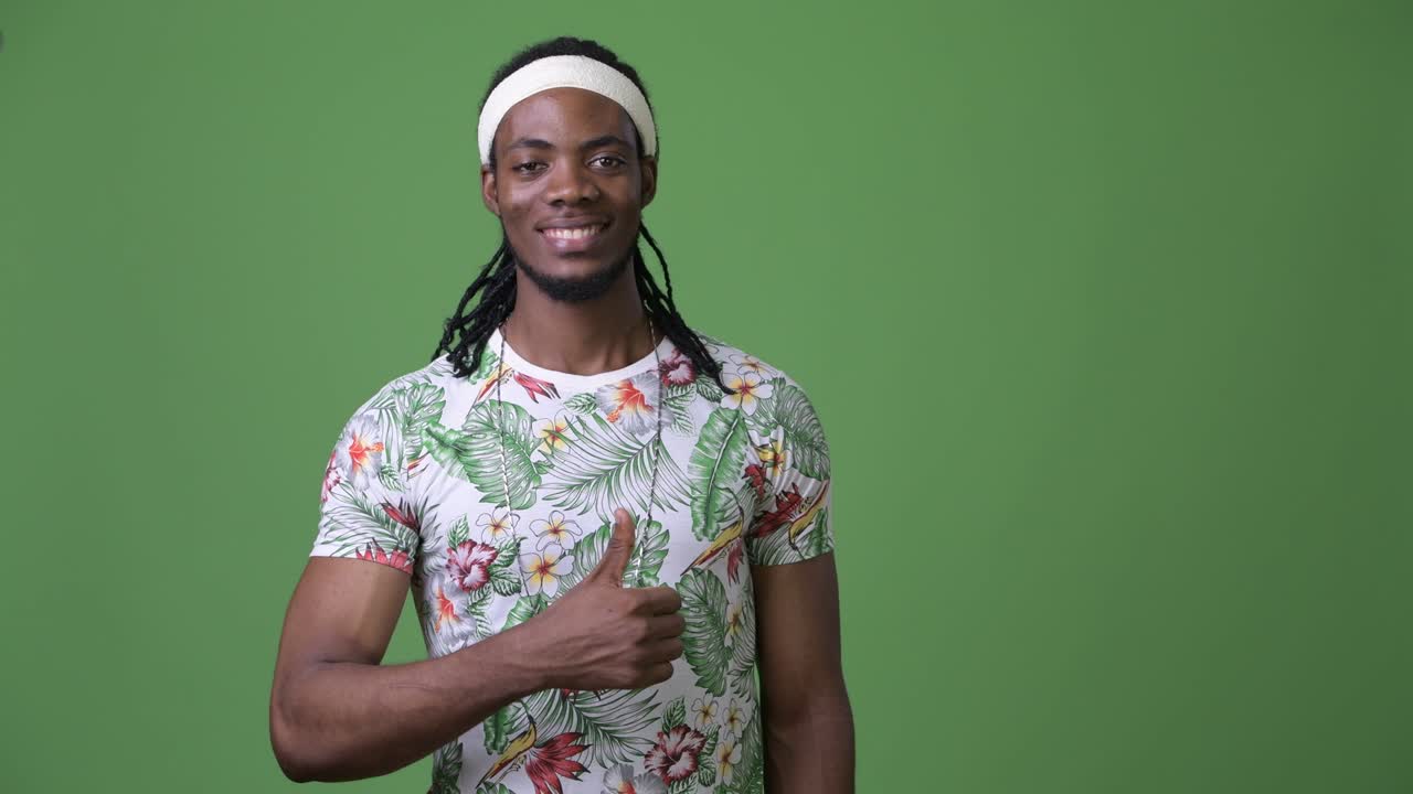 joven hombre africano guapo con dreadlocks contra un fondo verde