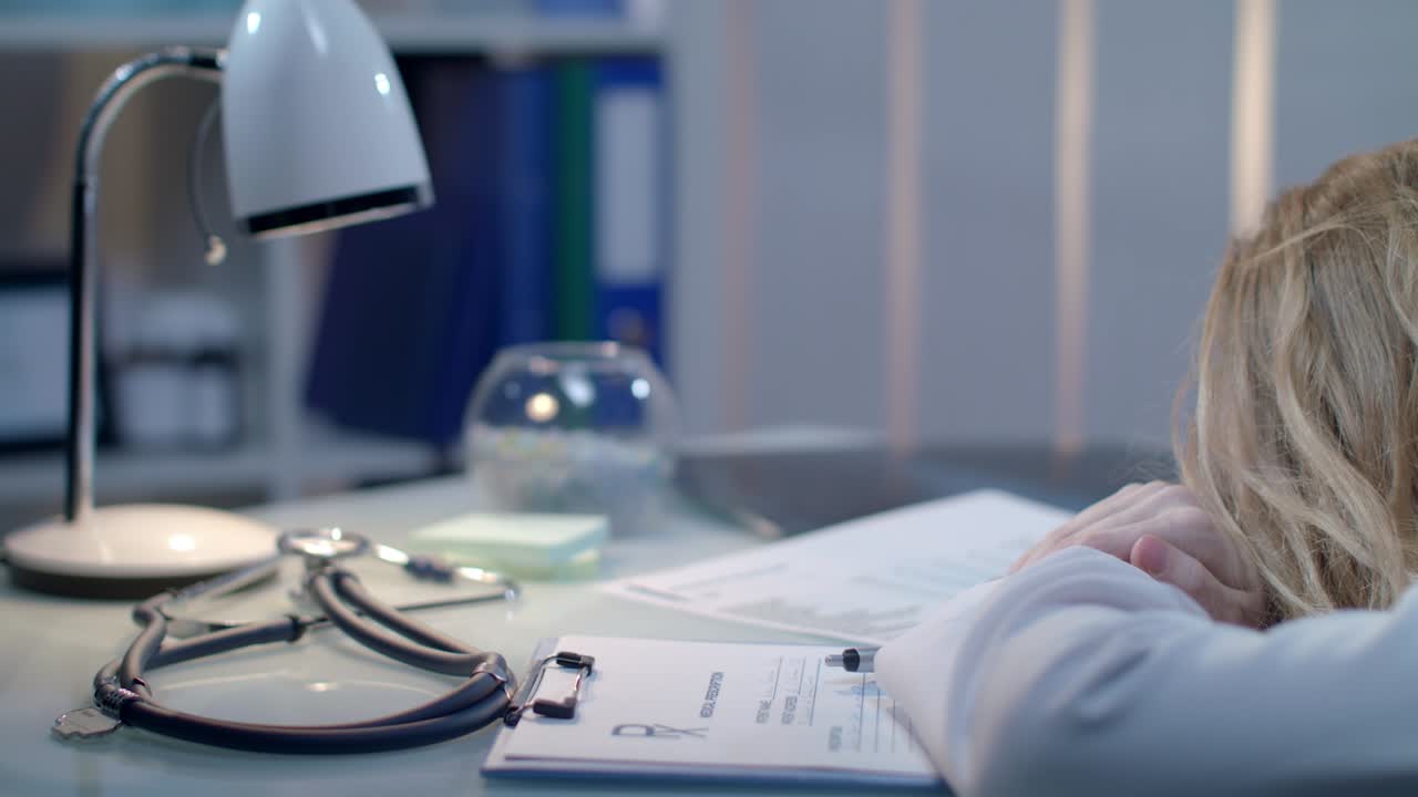 Tired doctor sleeping at medical workplace. Medical specialist tired at work