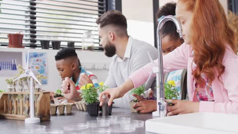 diverse male teacher and happy schoolchildren studying plants in school classroom