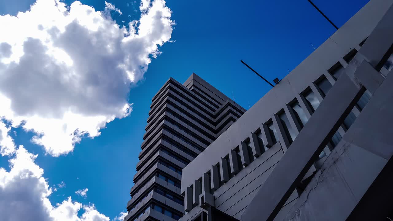 Tilt-up motion time lapse of German citizen office, high-rise public building against sunny blue sky