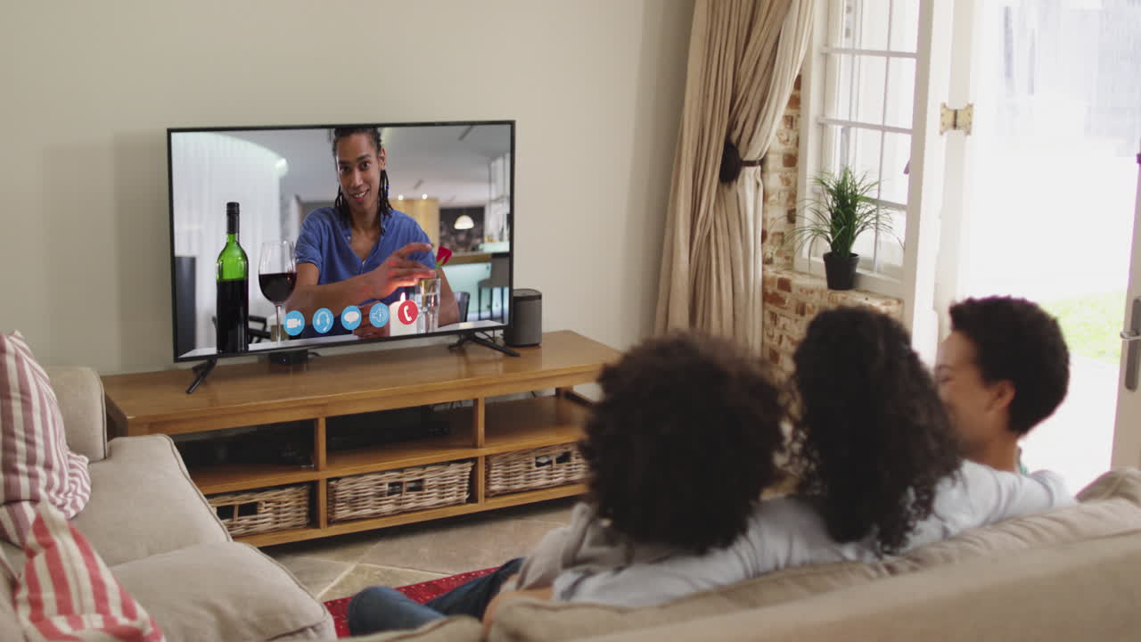 아프리카계 미국인 가족 이 집 에서 소파 에 앉아 tv 에서 비디오 통화 를 하고 있다