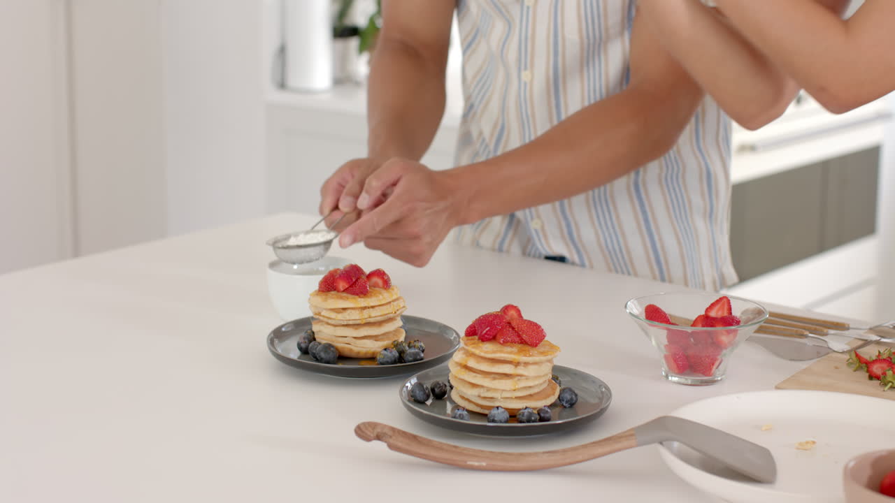In modern kitchen, preparing pancakes with fresh strawberries and blueberries, at home