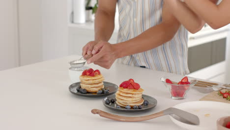 In modern kitchen, preparing pancakes with fresh strawberries and blueberries, at home