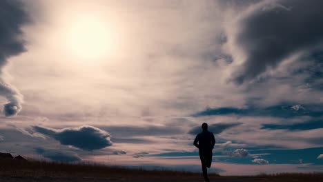 Striking-black-silhouette-outline-of-a-male-jogger,-jogging-against-a-dramatic-sky