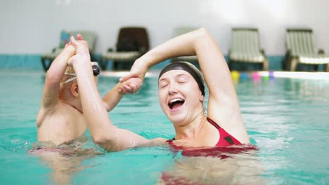 slow motion shot of happy smiling little kid swimming together with his mother in the swimming pool. young mother is turning him