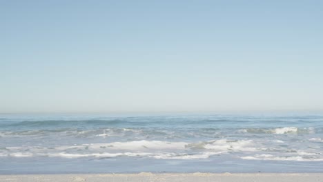 Cielo-Azul-Sobre-El-Mar-Con-Olas-Contra-La-Playa-En-Un-Día-Soleado