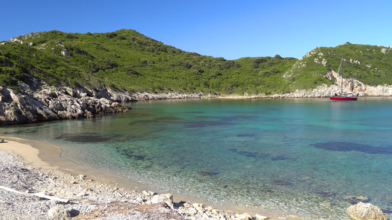 toma panorámica suave de un velero en las aguas cristalinas de la playa de porto timoni en la isla de corfú.