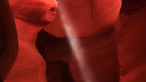 panup of as a shaft of light illuminates the red rock walls of a enclosed geological formation in antelope canyon arizona