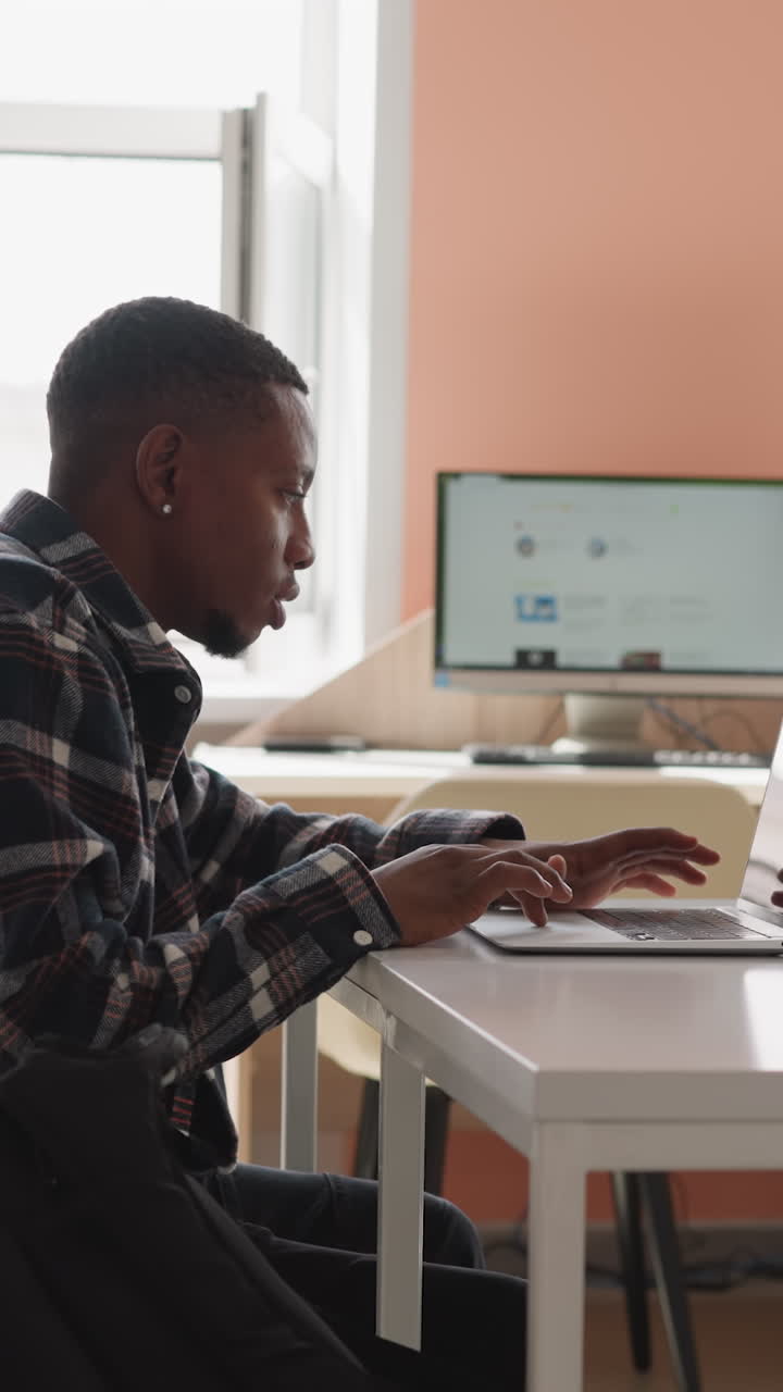 Man works with laptop in computer class. Black guy immersed in internet surfing uses college laptop equipment for seeking. Preparation with technology