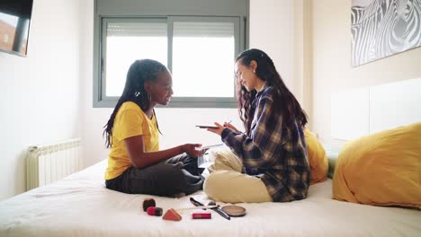 two women applying makeup in a bedroom