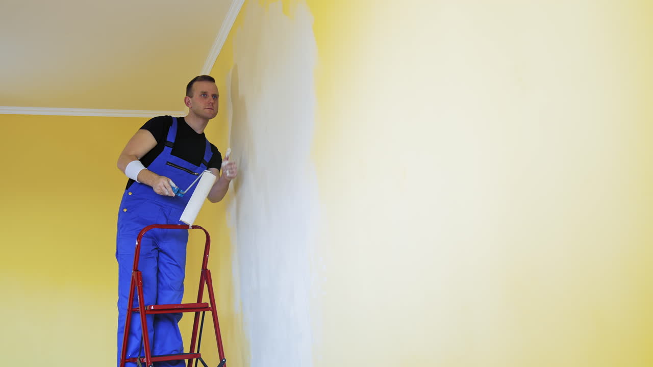 Man paints walls in apartment. Caucasian man paints the wall with roller
