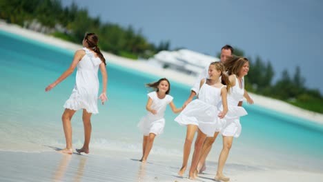 caucasian parents and their female children enjoying beach
