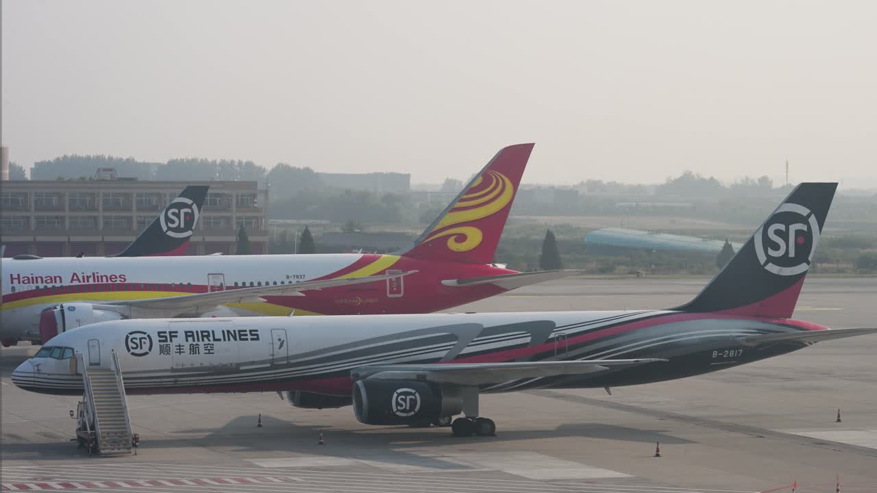 During dusk at Beijing International Airport, China, airplanes from Hainan Airlines, a prominent Chinese airline, and SF Express, a global delivery and logistics company, are parked on the runway.