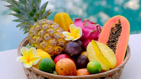 tropical exotic in a basket. fruit on wooden table and swimming pool background