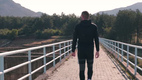 Man-walking-on-a-dam-sightseeing-the-beautiful-nature-slow-motion