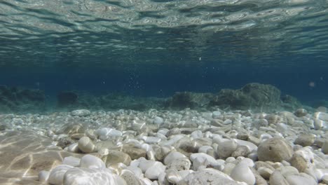 Stone-Drop-On-Crystalline-Water-Of-Emplisi-Beach,-Kefalonia-Island,-Greece