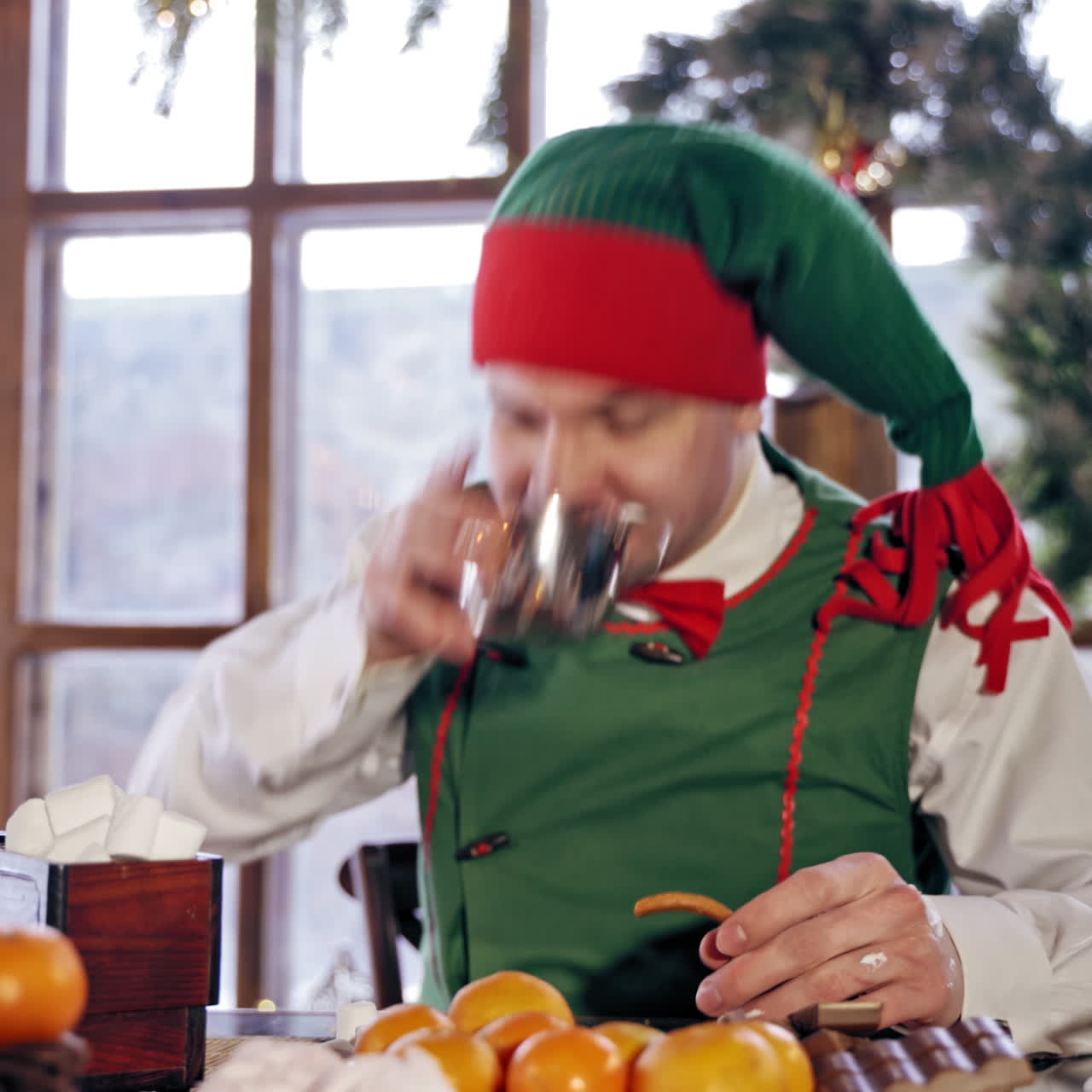 Elf eating at a table. Santas elf eating Christmas dinner in a decorated room. New Year celebration. Christmas eve.