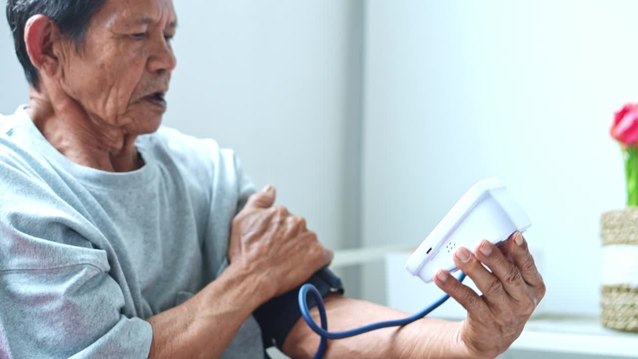 Elderly man checking blood pressure at home focusing on health and well-being monitoring