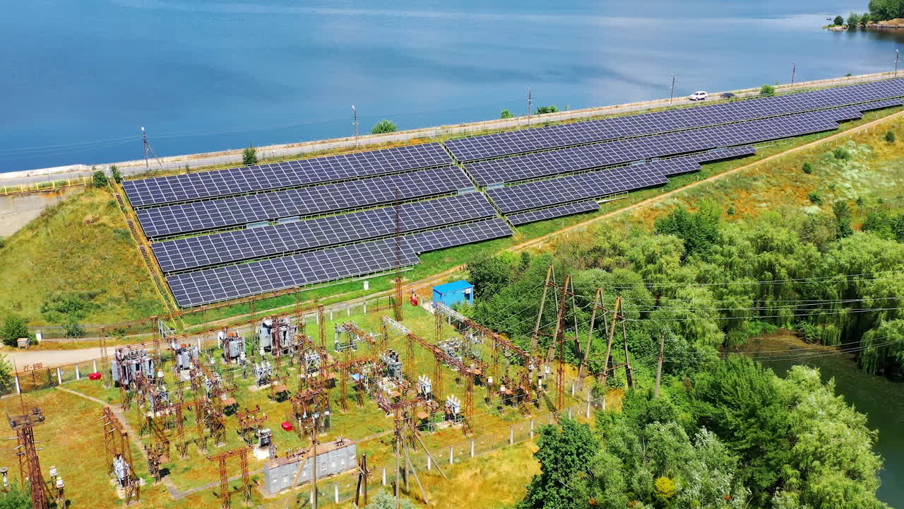 Solar power station near river at sunny day. Some solar panels in rows for power Production. Renewable green energy. Alternative energy sources. Top aerial view