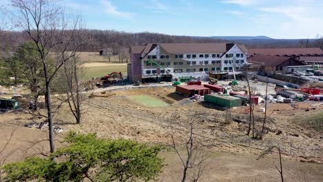 aerial push in over the trees revealing cacapon state park lodge expansion construction in the mountains of west virginia