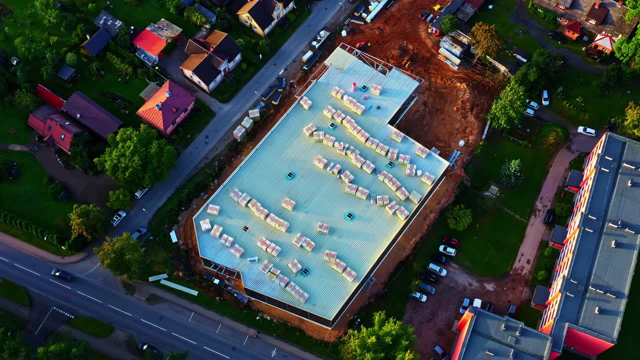 Top View of Modern Building Construction With White Metal Roof and Stacked Panels
